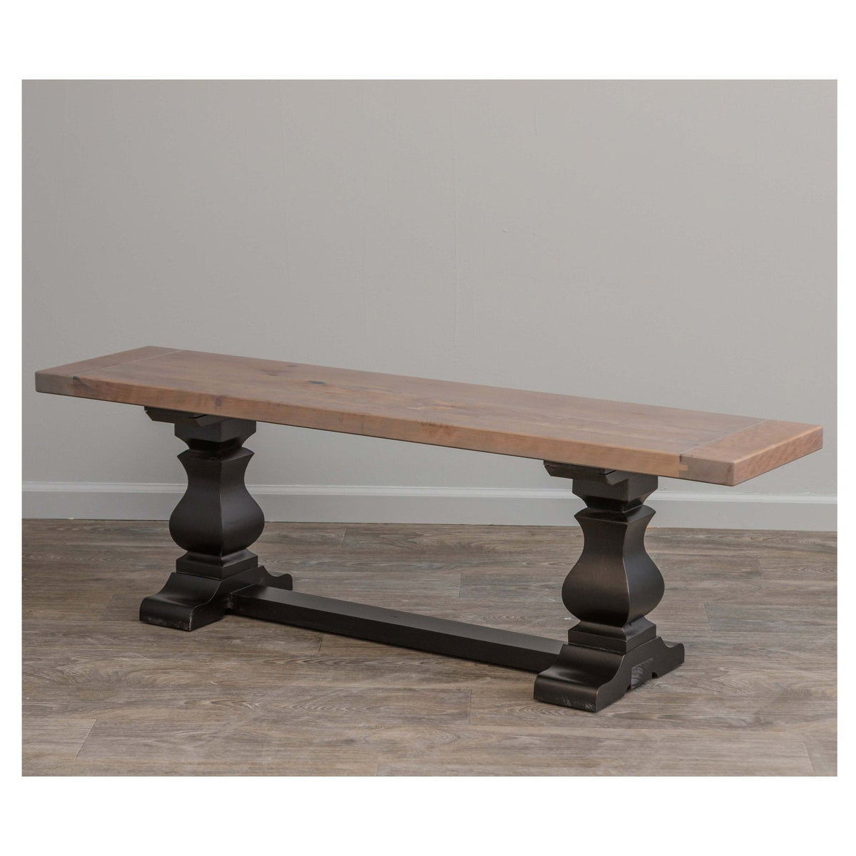 Trestle dining bench with a driftwood gray plank seat resting on two black urn pedestals and a stretcher base
