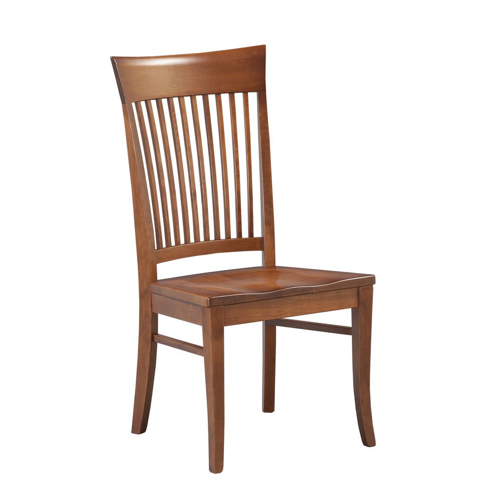 Cherry slat back dining chairs with solid wood seats around a turned leg farmhouse table by a brick wall