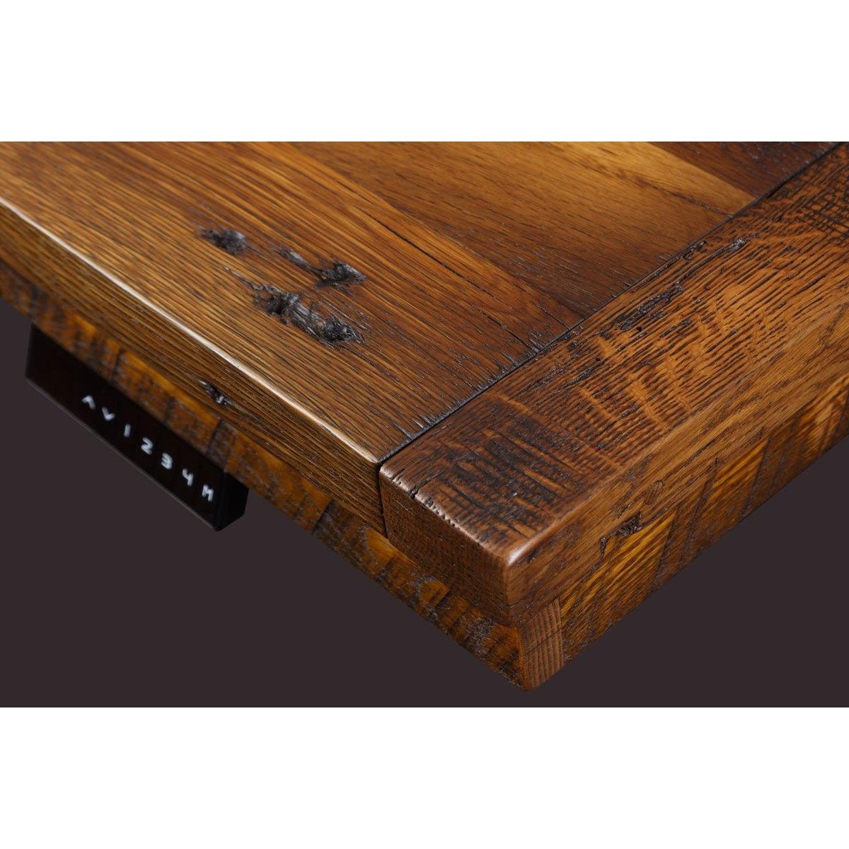 Corner detail of the reclaimed oak desk top showing knots, saw marks and the black height control keypad