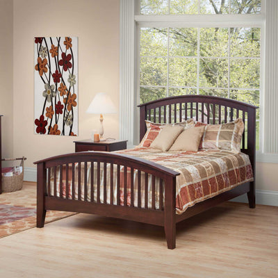 Espresso arched spindle bed with a curved slat headboard and footboard, styled with a tan patchwork quilt