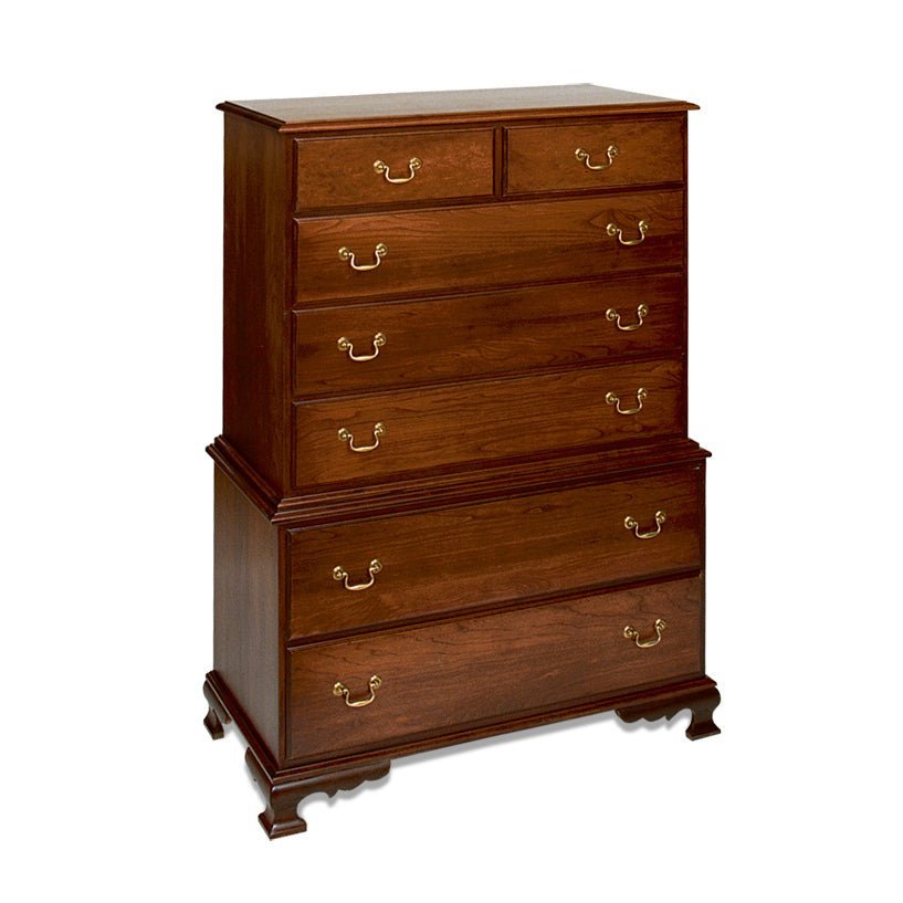 Cherry chest on chest with seven drawers and brass bail pulls beside a turned-post bed, basket of flowers on top