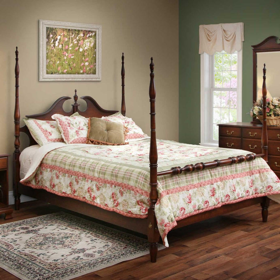 Turned post cherry bed with pediment headboard styled with a green plaid and rose quilt beside a dresser mirror