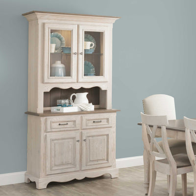 Whitewashed china cabinet with lighted glass doors displaying dishes above a two door buffet base