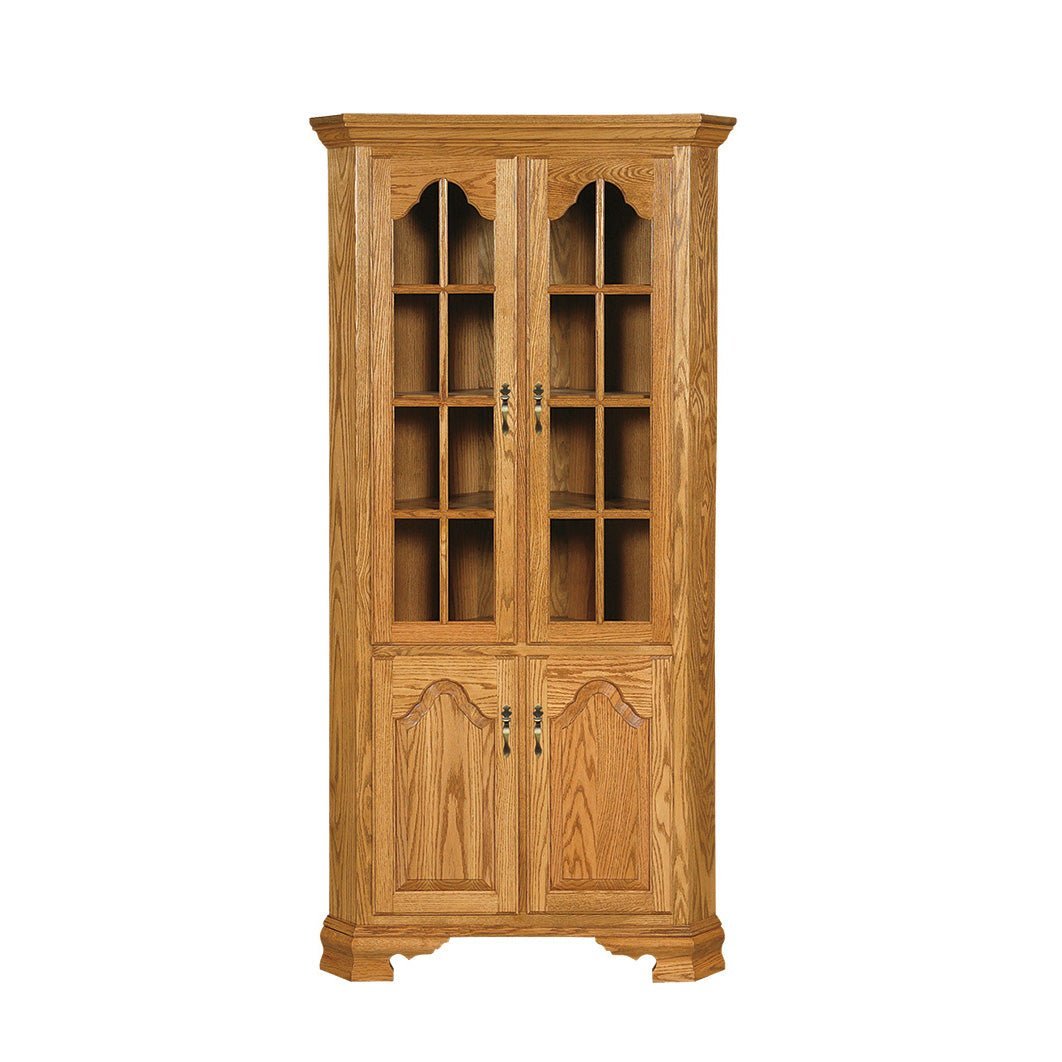 Front view of a golden oak corner china cabinet with tall twelve-pane glass doors and arched trim over paneled base doors