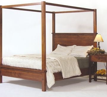 Dark cherry canopy queen bed with tall square posts and a paneled headboard beside a one-drawer night table