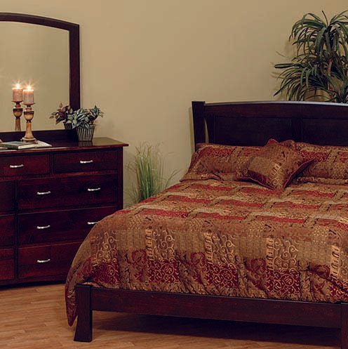 Dark espresso bedroom set with a curved headboard bed, mirrored dresser and candles in a warm-lit room