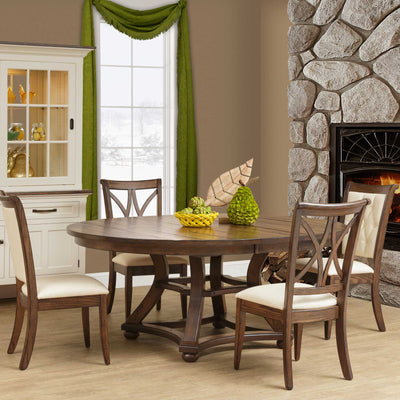 Round expandable dining table in a rustic brown finish with a curved trestle base and four upholstered chairs