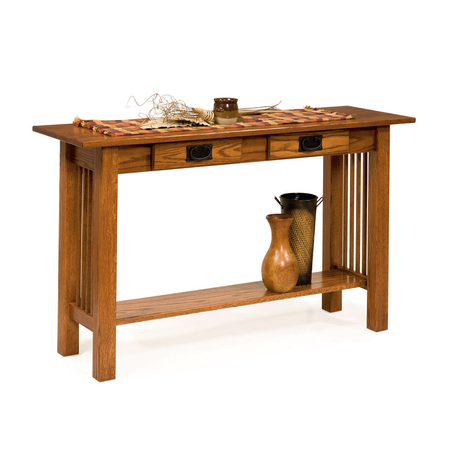 Oak Mission console table with two drawers, black bail pulls, slat sides and a lower shelf holding pottery
