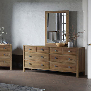 Six drawer dresser with rectangular mirror in light natural wood with square nickel knobs in a plaster wall bedroom