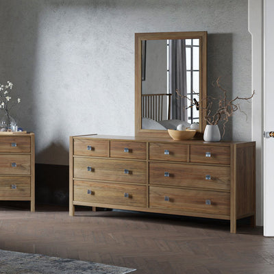 Six drawer dresser with rectangular mirror in light natural wood with square nickel knobs in a plaster wall bedroom
