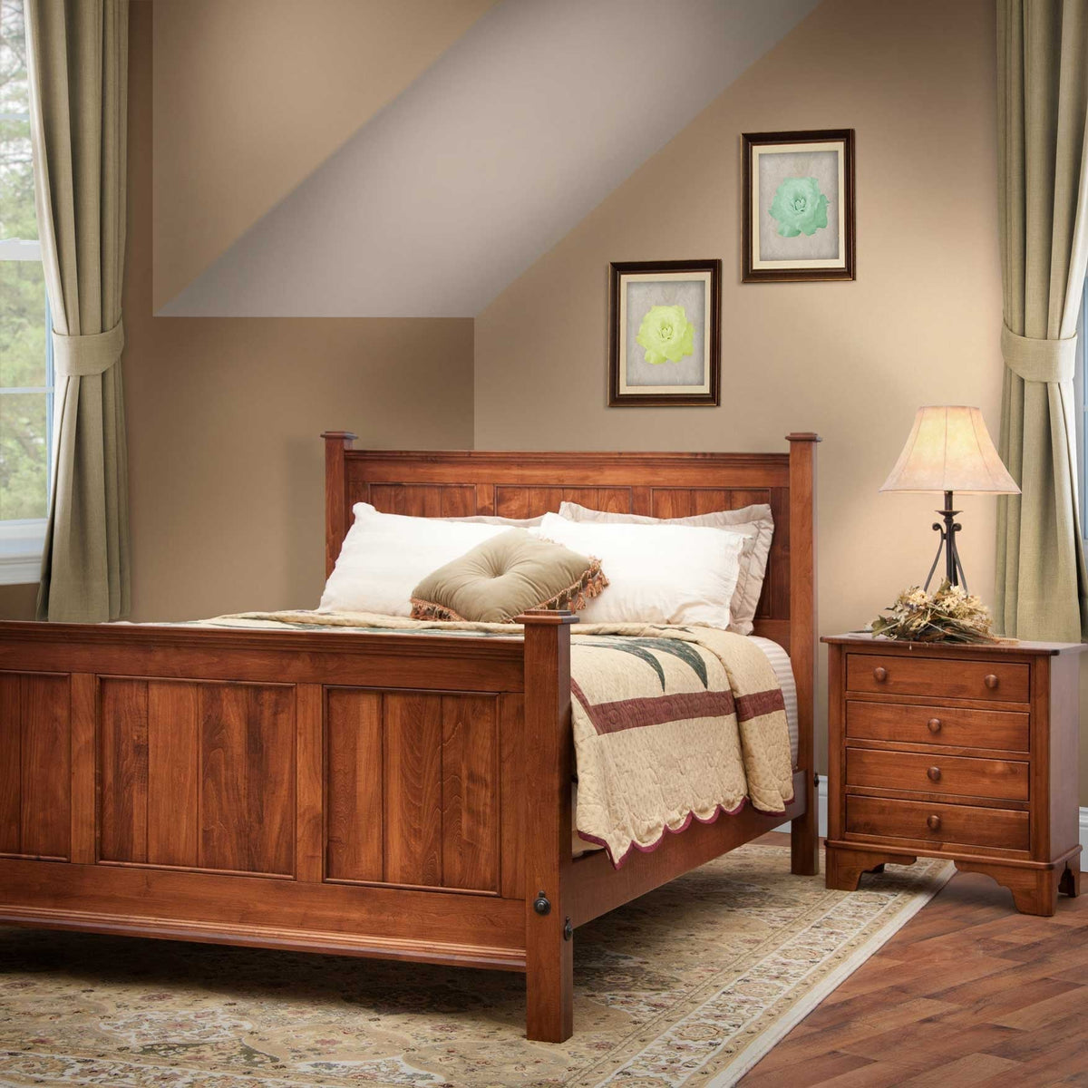Cherry panel bed with a four-drawer nightstand and lamp in a bedroom with sloped ceiling and framed prints