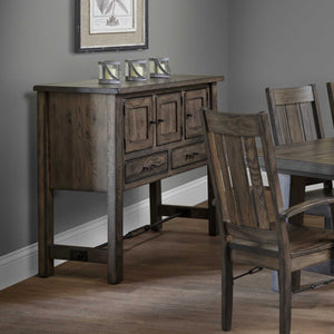 Gray oak dining sideboard with three panel doors, two drawers and an iron stretcher beside a dining set