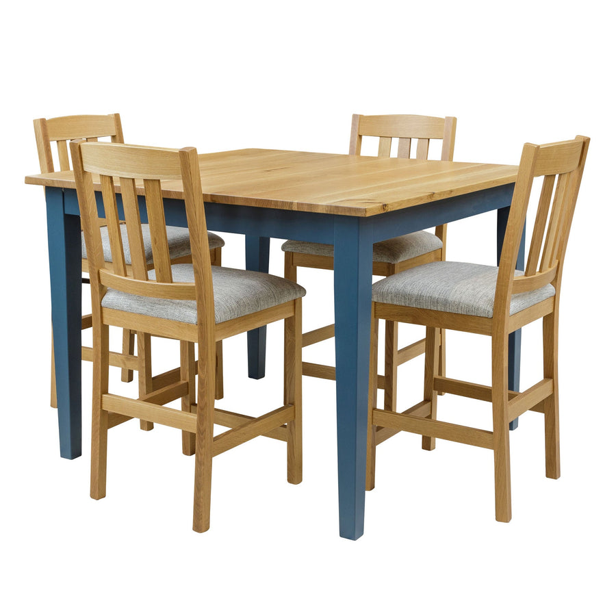 Counter height gathering table with a natural oak top and navy blue painted legs, with four gray upholstered slat back stools