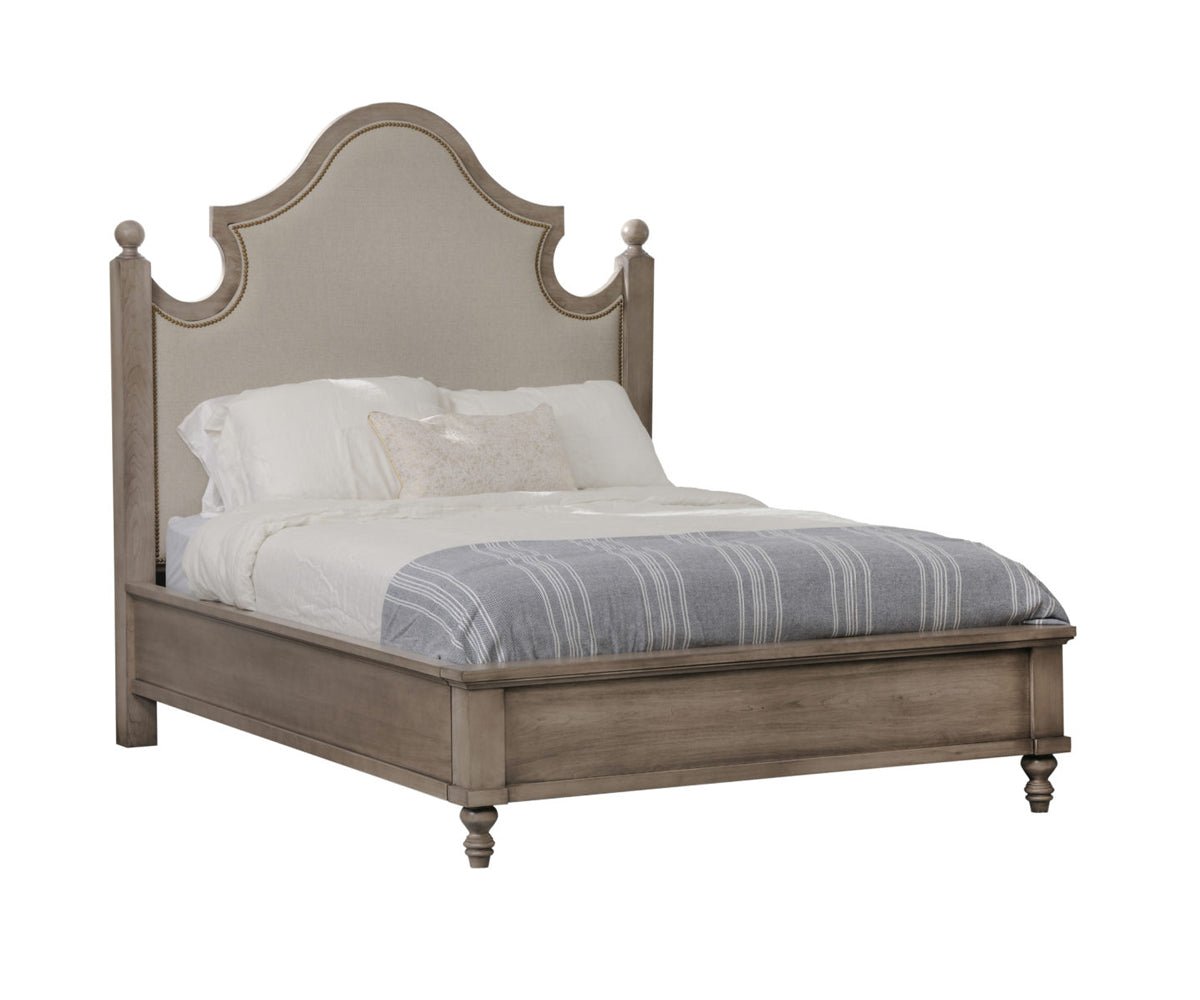 Taupe upholstered panel bed with arched linen headboard, nailhead trim, ball finials and turned feet on white