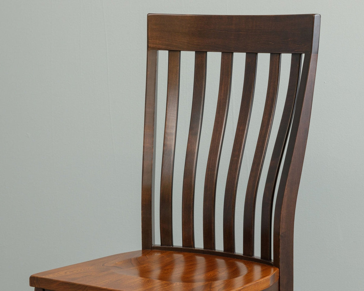 Close-up of a two-tone chair back with slim curved slats in dark stain above the glossy cherry wood seat