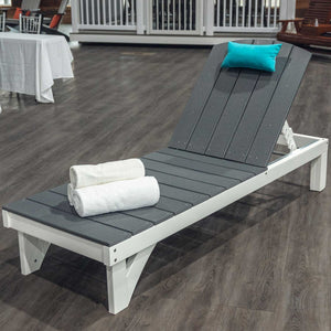 Gray and white poly chaise lounge with adjustable slat back, teal pillow and rolled towels on a showroom floor