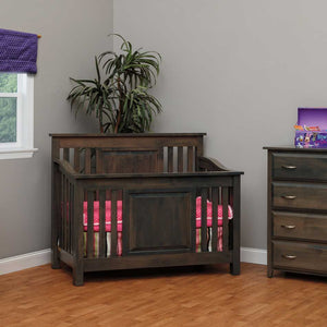 Charcoal gray Darlington crib with mission slat sides and a raised panel front, pink bedding, beside a matching chest