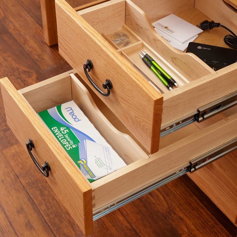 Two open desk drawers in oak showing dovetailed maple boxes, divided pencil tray and metal drawer slides