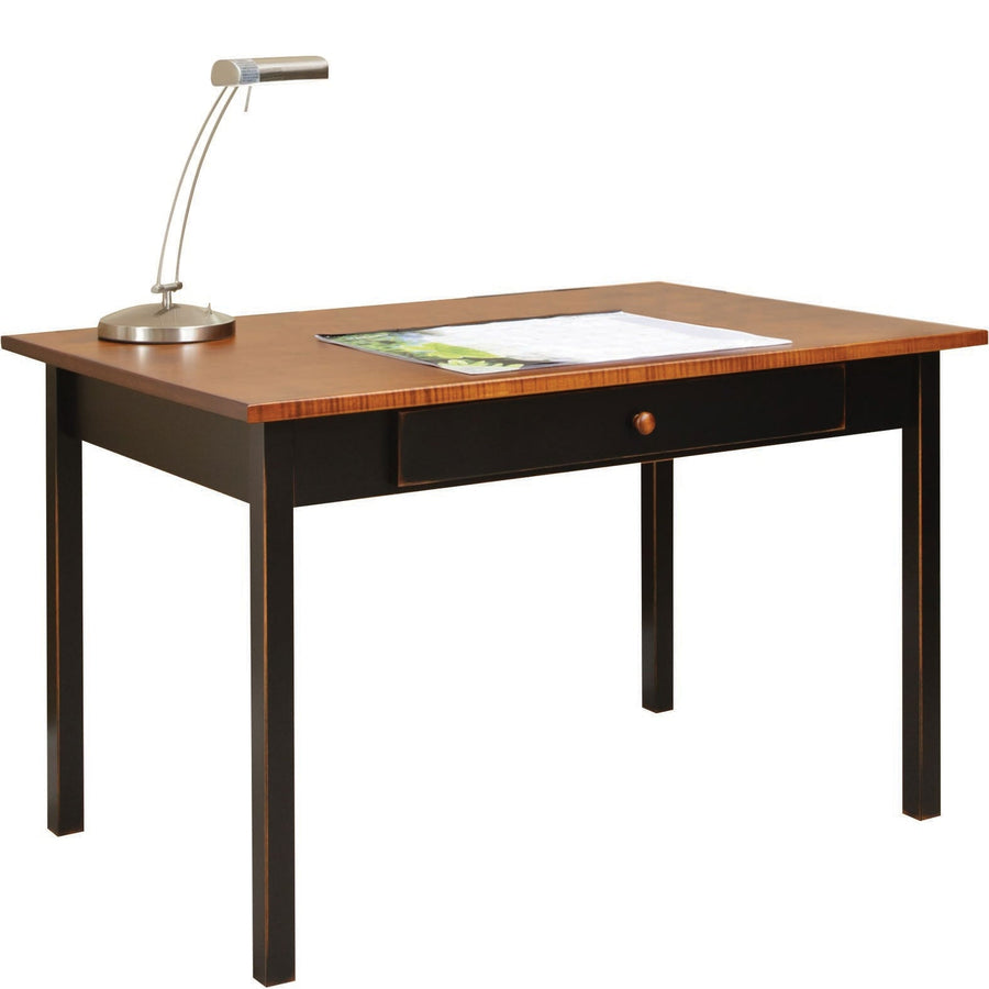 Two-tone table desk with a golden wood top, distressed black base and single drawer, styled with a desk lamp