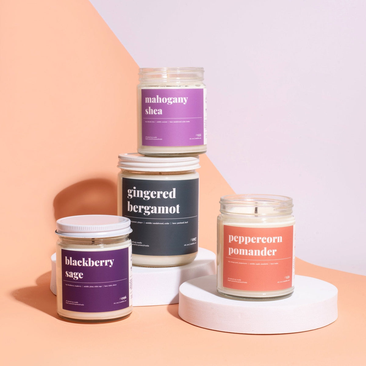 Mahogany shea, gingered bergamot, blackberry sage and peppercorn pomander candles staged on white risers