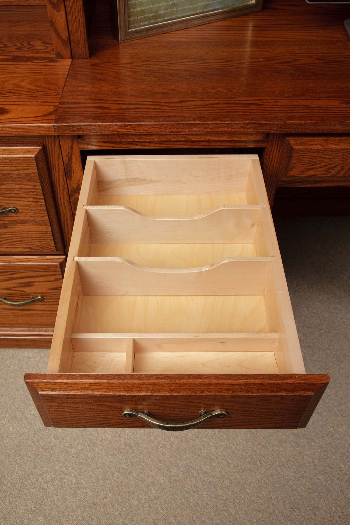 Oak desk drawer opened to reveal a maple insert tray with slotted file dividers and pencil compartments