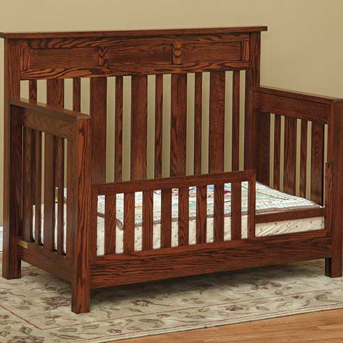 Hudson crib set up as a toddler bed with slatted safety rail and quilted mattress on an area rug