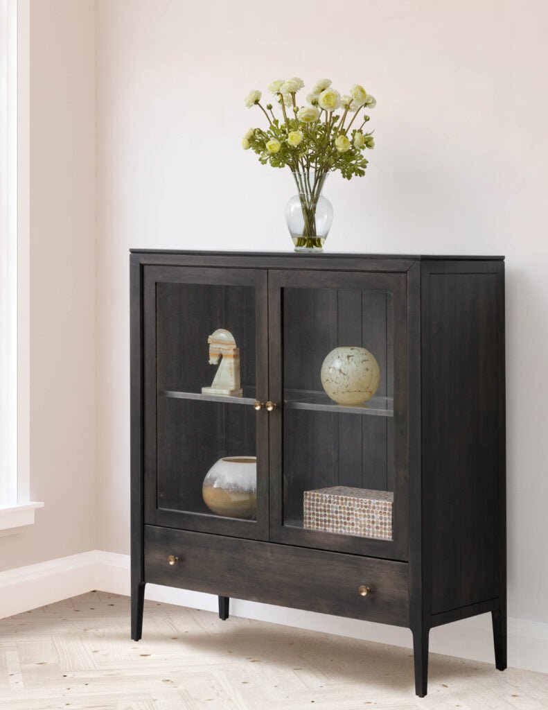 Charcoal painted two door display cabinet with glass doors, glass shelf and a lower drawer with brass knobs