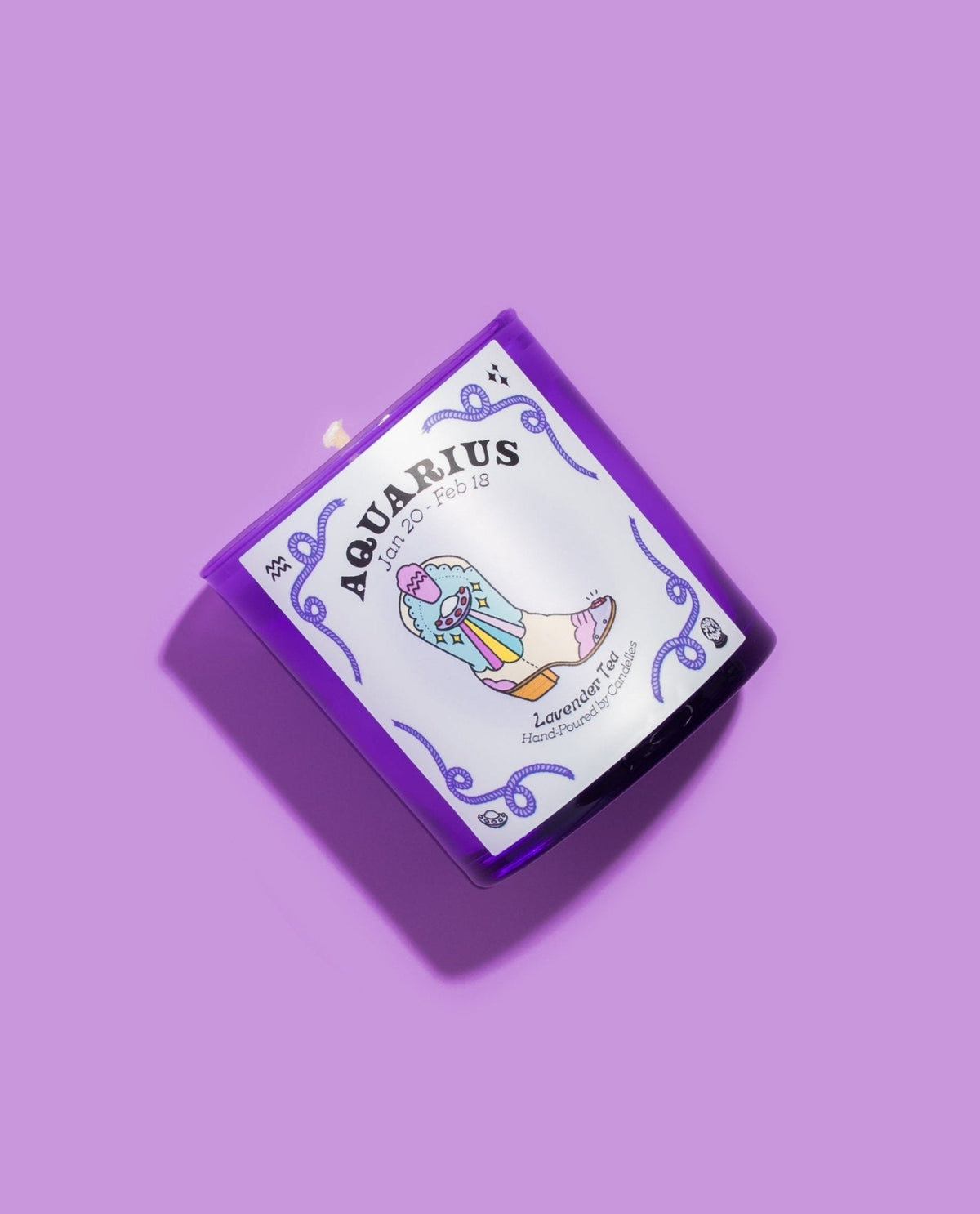 Aquarius lavender tea zodiac candle tipped on lilac, showing the rainbow cowboy boot illustration on the label