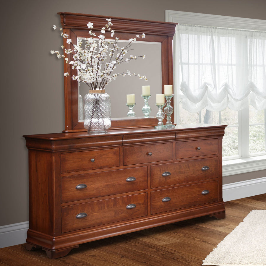 Cherry triple dresser and mirror styled with candles and blossoms beside a curtained bedroom window