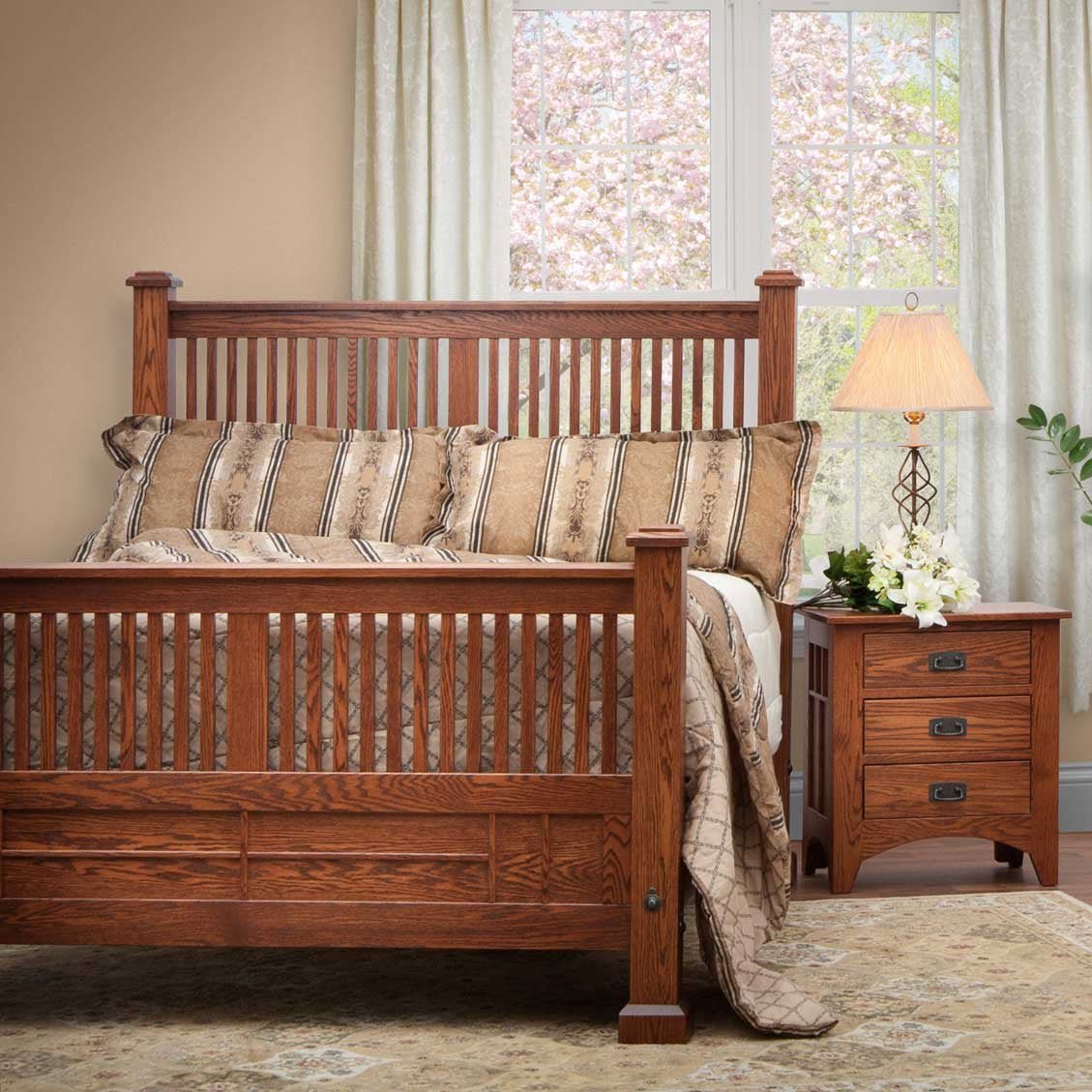 Mission oak spindle bed with slatted headboard and footboard, dressed in striped bedding beside a nightstand