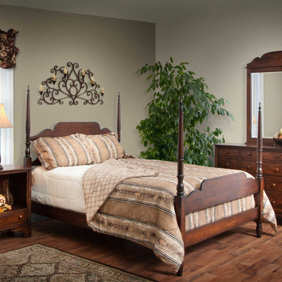 Cherry four-poster bed with turned finials and scalloped headboard styled with striped bedding and a nightstand
