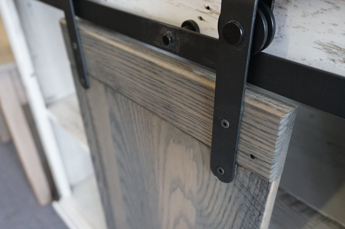 Close up of the black barn door track and roller hardware on the reclaimed wood tv stand