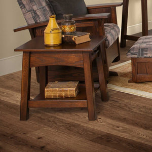 Dark brown Santa Fe end table with drawer and lower shelf holding pottery and antique books on wood flooring