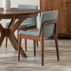 Walnut mid century dining chairs upholstered in sea-green fabric around a round walnut table