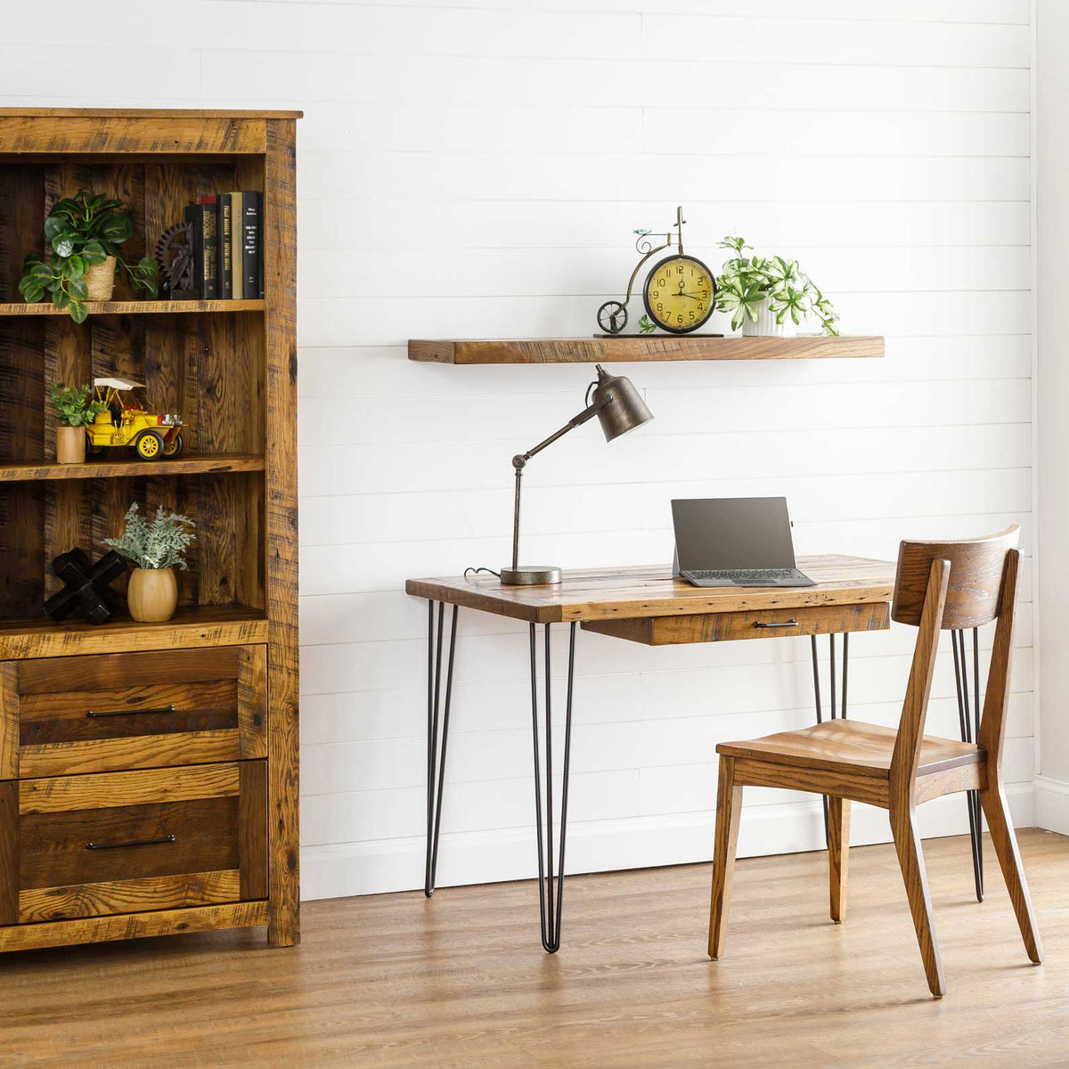 Reclaimed wood hairpin writing desk with laptop and lamp beside a barnwood bookcase and wooden chair in a shiplap office
