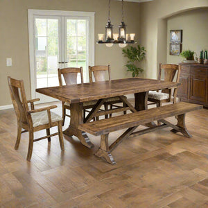 Westin trestle dining table with bench, panel back chairs and arm chair under lantern pendants in a tiled dining room