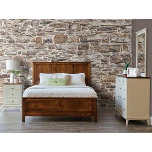 Panel bed with raised-panel headboard and footboard in a rich brown finish, styled in a stone-walled bedroom