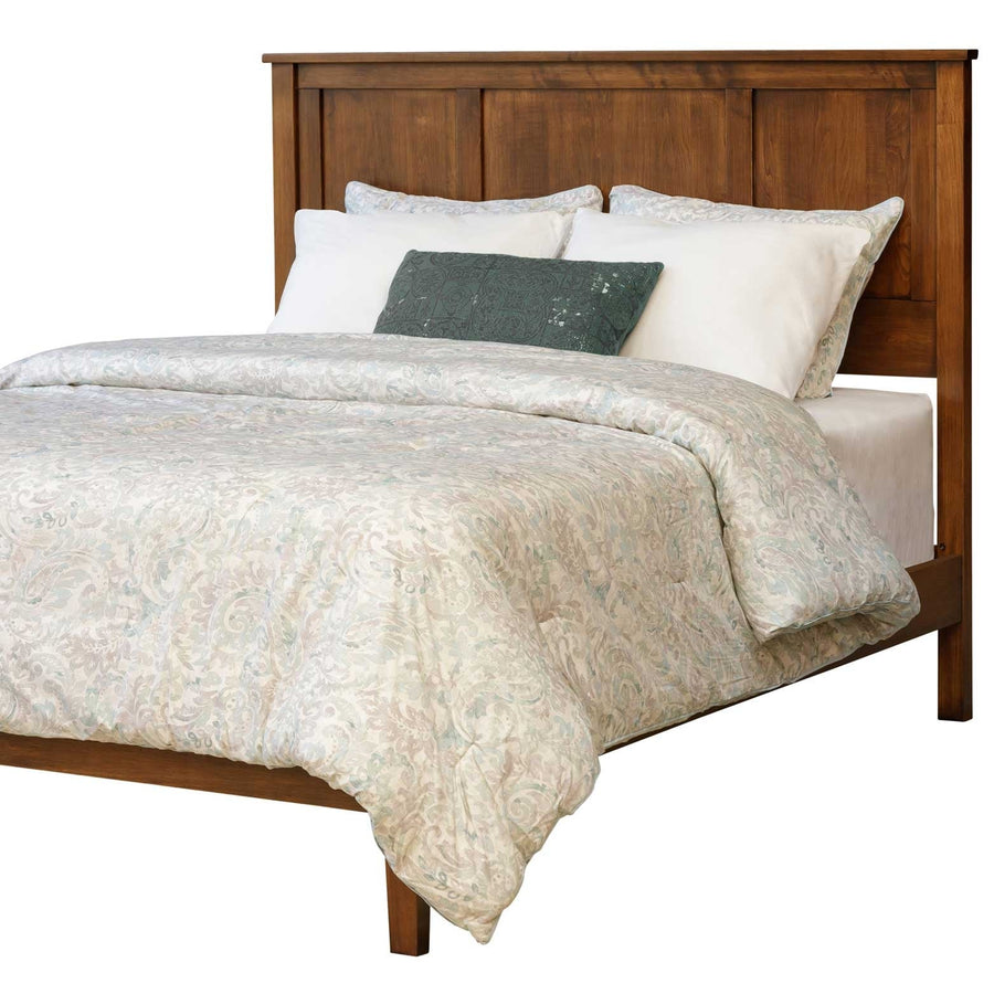 Panel bed with a low footboard, three-panel headboard and warm brown solid wood frame with paisley bedding