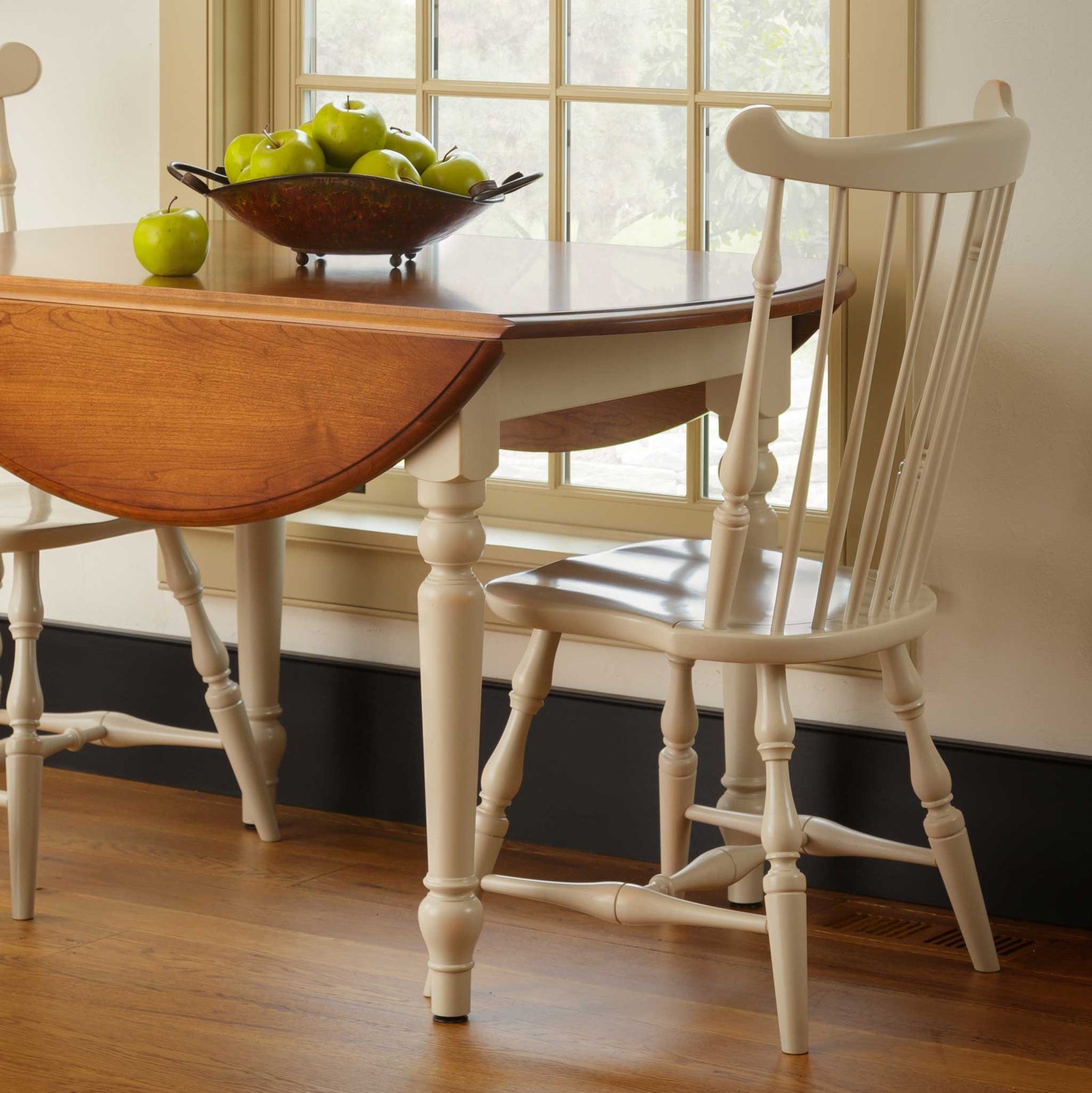 Wooden chair and table set in a room with white paneled walls.
