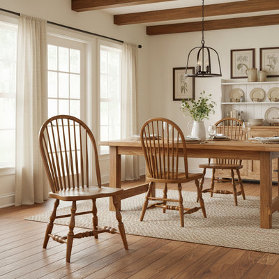 Oak Windsor dining chairs with bowed spindle backs and turned legs around a farmhouse table in a bright beamed dining room