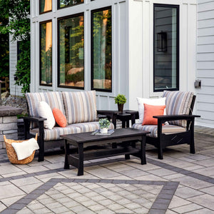 Black poly patio loveseat and chair with striped cushions around a matching coffee table and end table