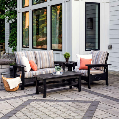 Black poly patio loveseat and chair with striped cushions around a matching coffee table and end table