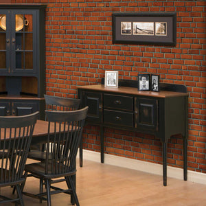 Distressed black sideboard with oak top and back gallery, two drawers, two doors and tall tapered legs in a brick dining room