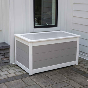 White and gray poly deck box with plank lid and horizontal panels beside a window on a paver patio