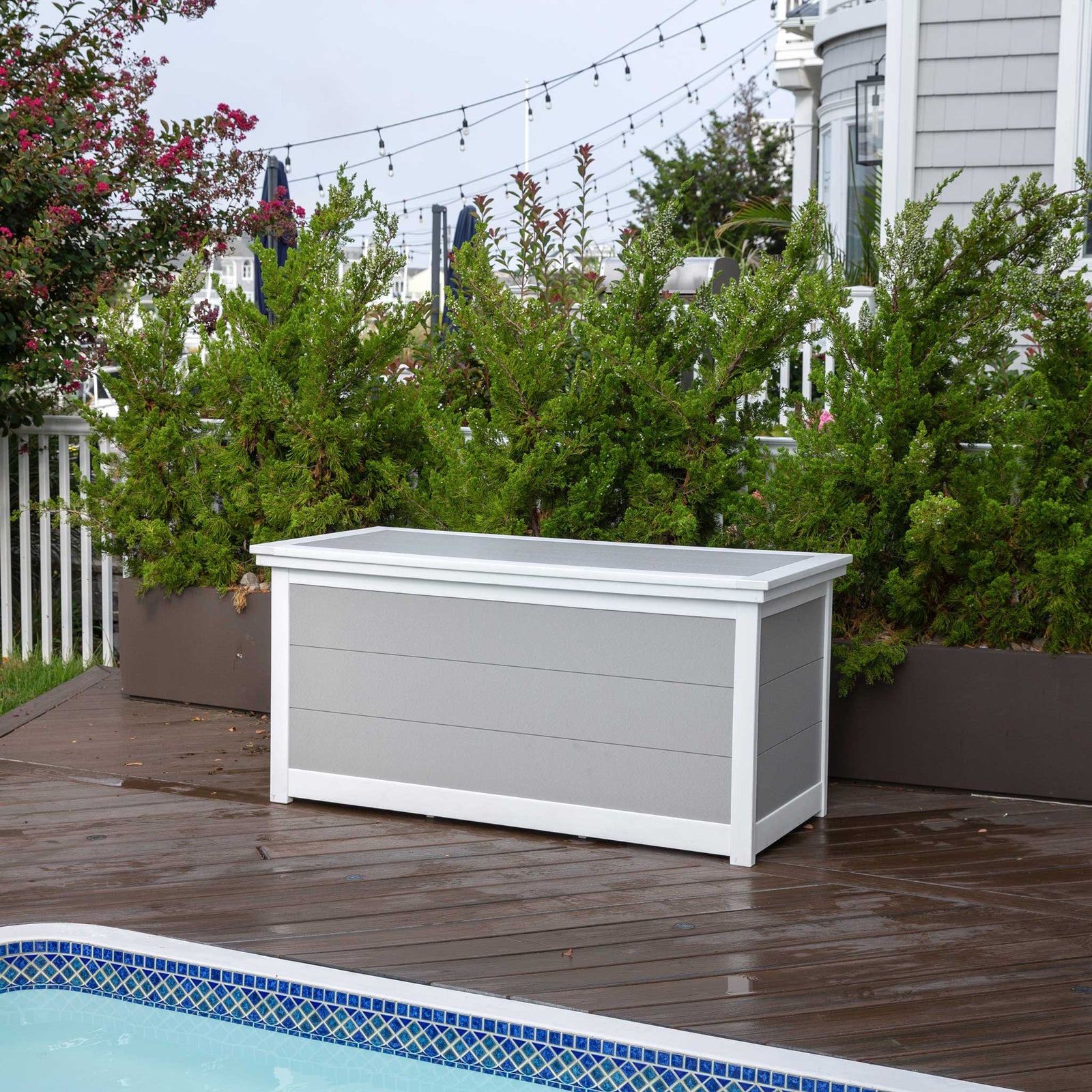 Turquoise and white five foot poly cushion storage box with plank lid on a paver patio by white siding
