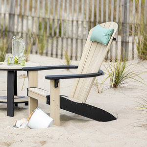 Weathered wood poly Adirondack chair with black arms and a teal pillow, set in beach dune grass