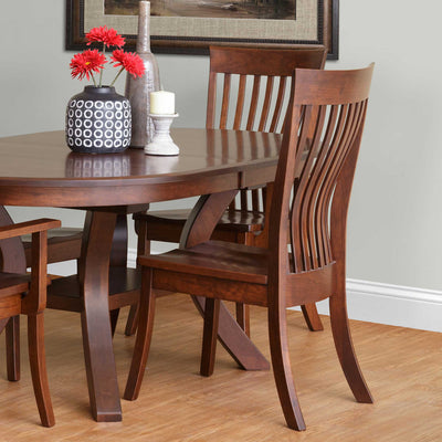 Lumbar dining chairs with curved vertical slats and wood seats at a cherry finished pedestal dining table