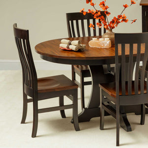 Two-tone dining chairs with black painted frames and cherry wood seats around a round pedestal table with fall florals