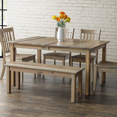 Natural finish expandable leg dining table with slat back chairs and matching bench against a white brick wall