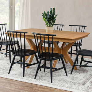 Light oak expandable dining table with crossed splayed pedestal legs and six black spindle back chairs